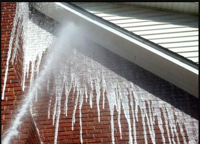 A water jet spraying out of the side of a building.